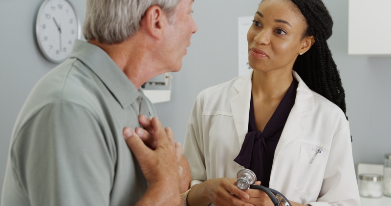 Doctor listening to patient while sitting on a refurbished medical exam table